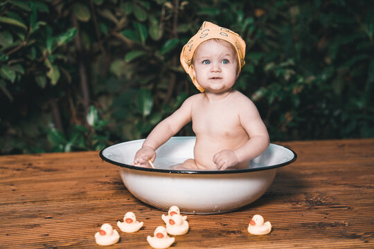 Baby sitzt nackig in einer Waschsch&uuml;ssel im Garten mit gelben Quitscheenten vintage Var. 2