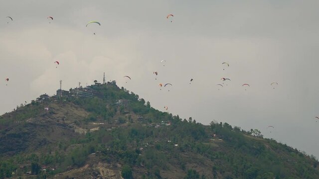 Wide shot of group of paragliders in mountains, Pokhara, Nepal