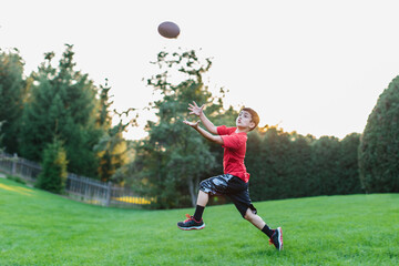 Young boy playing football in a backyard