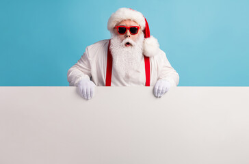 Portrait of his he nice attractive funky amazed stunned white-haired Santa holding in hands copy space board advert ad attention isolated over bright vivid shine vibrant blue color background