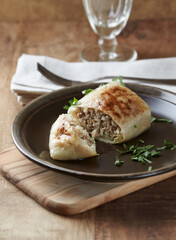Stuffed cabbage roll - popular Polish dish on rustic wooden background. Close up. 