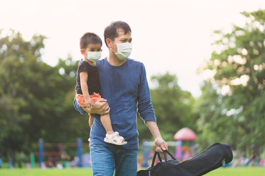 Asian Father And Son Are Wearing The Face Mask While The Are Walking And Enjoying For Outdoor Activity, Concept Of Social Distancing And Using Of Ppe In The Public Place In The Covid19 Virus Outbreak.