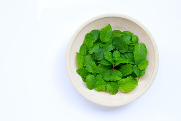 Fresh mint leaves in pottery plate on white background.