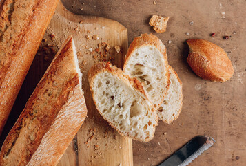 Homemade french two Baguette loafs and cut slice on wooden cutting board