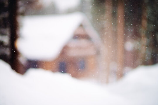 Blurred image of a cabin surrounded by snow and falling snowflakes