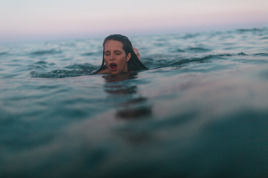 Young woman swimming gasps for air