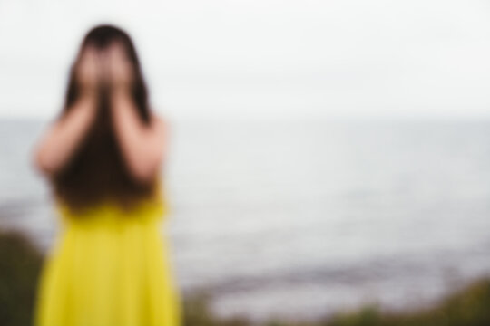 De-Focused Girl in Yellow Dress Covering Her Face with Her Hands