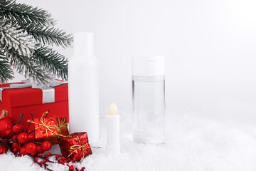 Skincare cosmetics bottles on snow covered surface. Winter season cosmetics. Blank containers with gifts and fir twigs backdrop. Christmas present for women idea. Banner. Copy space