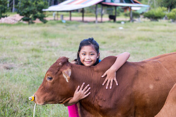 An Asian girl lovingly hugs her cow in a ranch. The concept of animal love.