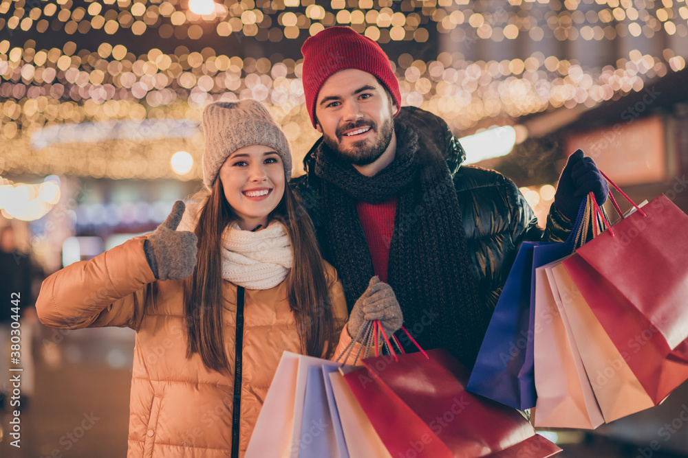 Sticker Black friday. Photo of two people students friends hold shopping bags show thumb up sign under x-mas christmas outside illumination