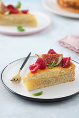 Piece of cheesecake with raspberries and figs on grey background.