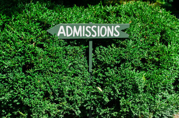 sign pointing to admissions against a green backdrop
