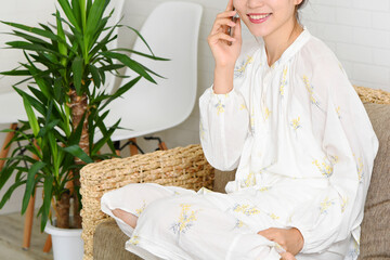 ソファーの上で電話をかける若い女性