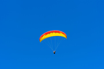 Paraglider in the blue sky. The sportsman flying on a paraglider.