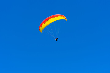 Paraglider in the blue sky. The sportsman flying on a paraglider.