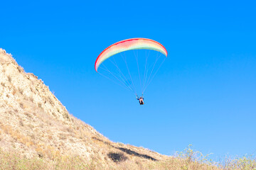 Paraglider in the blue sky. The sportsman flying on a paraglider.