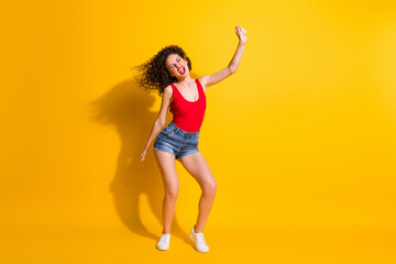 Fototapeta na wymiar Full length body size photo of funky pretty nice girl with curly hair dancing celebrating singing wearing jeans mini shorts tank-top isolated on vivid yellow color background