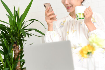 ソファーの上でスマホを操作する若い女性