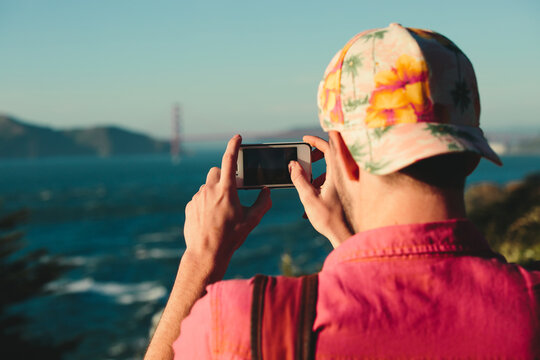 young man takes a photo of scenic landscape