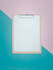 Blank clipboard on pink and cyan background.