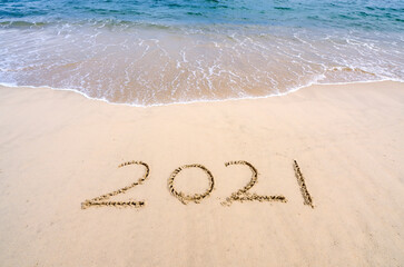 Fototapeta na wymiar 2021 year message handwritten in sand on beautiful beach background. New Years concept.