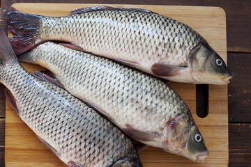 Three carps on a wooden cutting board