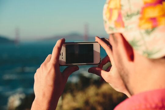 young man takes a photo of scenic landscape