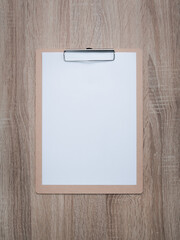 Blank clipboard on wooden desk background.