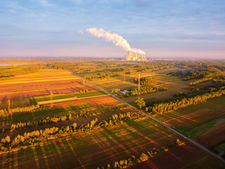 Agricultural fields with large power plant in a distance. Drone, aerial view.