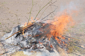 Big bonfire in the open air. A pile of ash from burnt boards and branches. Hot flame.