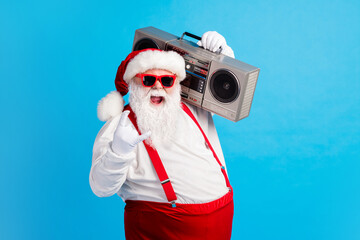 Fototapeta na wymiar Photo of cool stylish modern white grey hair bearded santa claus listen x-mas christmas music boom box show horned symbol wear red suspenders overalls isolated blue color background