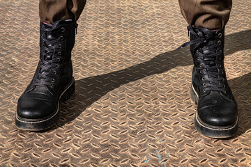 Legs of a man in berets. On the metal floor. Symbol: Aggressor. Cockiness.