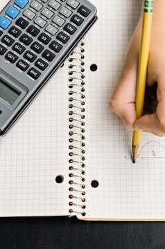 hand doing math in a notebook with calculator