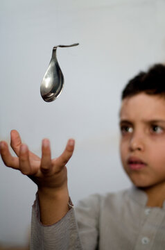 A boy bending a suspended spoon via telekinesis