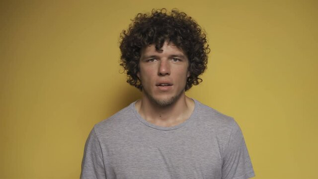 Young guy portrays a fright in the studio against an isolated background. He opens his eyes wide and grabs his heart. High quality.
