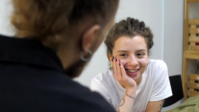 Pretty young woman with dreadlocks and tattoos flirts with a man. Conversation between a man and a woman in love. Family relationships. Hot adult girl and guy or boyfriend
