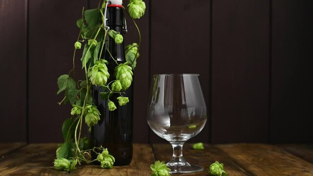 Beer. Cold Craft light Beer in a glass with water drops. Pint of Beer close up on a wooden background. Beer is pouring from the bottle. Border design. High quality 4k footage