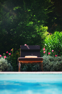 Poolside: sun towel on sun bed with flowering plants on background