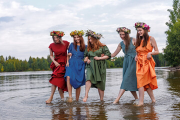Lovely girls in flower wreaths in nature. Ancient pagan origin celebration concept. Summer solstice...