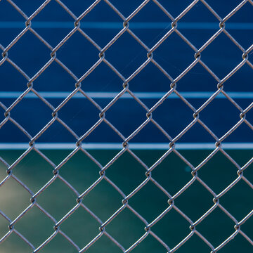 Close of up chain link fence, basketball court in background