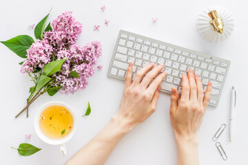 Female hands with laptop. Workplace with jasmine flowers top view