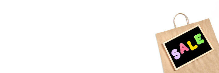 Word SALE written in bright colorful letters on black board on paper bag background. Banner.