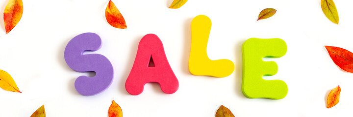 Word SALE written in bright colorful letters on background of autumn leaves. Banner.