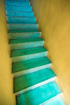 Bright yellow room with narrow turquoise stairs