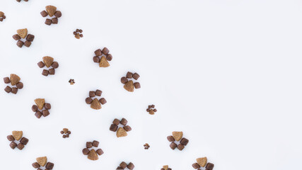 Diagonal frame of dry cat food in the shape of paws of different sizes on a white background.flat lay.copy space.The concept of proper nutrition for Pets.Minimalistic pattern