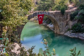 Stone bridge with the flag of Turkey over a mountain river