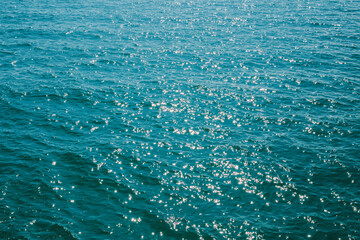 Background ocean wave with bokeh from sunlight reflected on water surface.