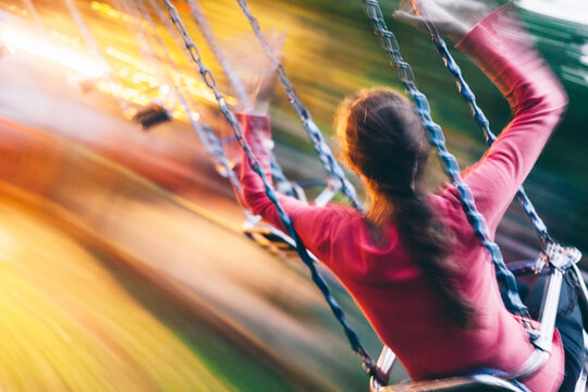 Young woman riding on a swing carousel in amusement park