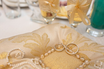 Wedding rings on a pillow and champagne in golden glasses