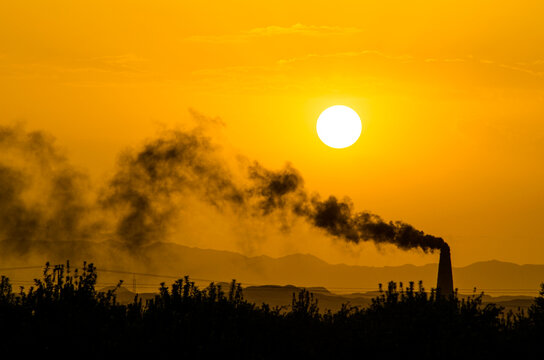 Smoke from a brik klin against a setting sun